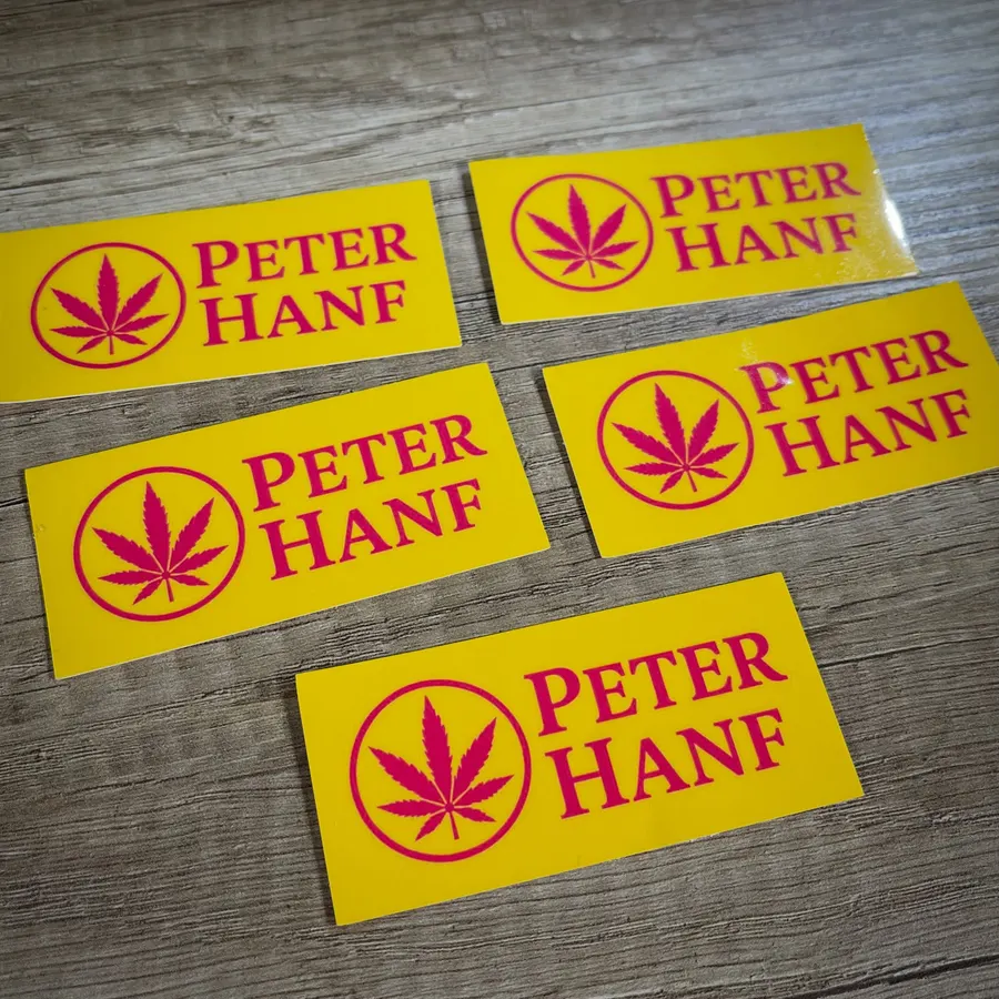 Gelbe rechteckige Aufkleber mit rotem Peter-Hanf-Schriftzug und Hanfblatt